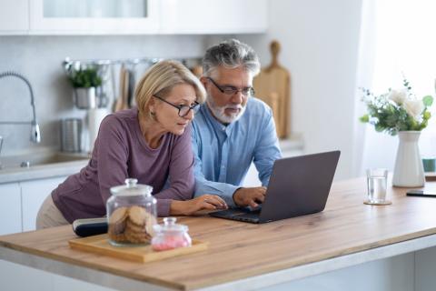 Couple fait des recherches sur les  dispositifs de défiscalisation depuis son ordinateur dans sa cuisine 
