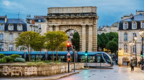 Passage du tram près de l’arche historique de Bordeaux au crépuscule