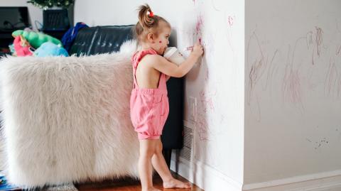 Une petite fille dessine avec un marqueur sur les murs blancs du salon
