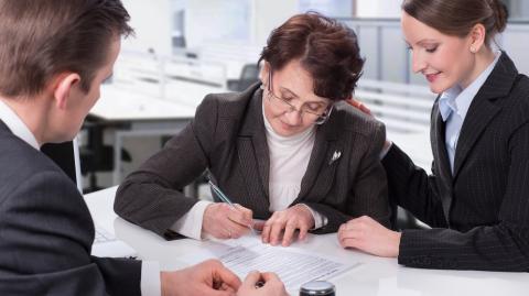 Une femme âgée signe un document officiel chez le notaire