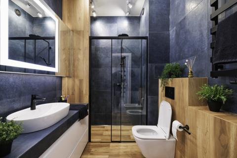 Belle salle de bain en carrelage bleu et meubles en bois. 