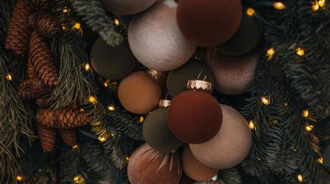 Boules de Noël allant du brun au safran accrochées sur un sapin