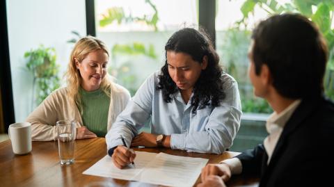 Un couple signe une offre d'achat sur les conseils d'un agent immobilier