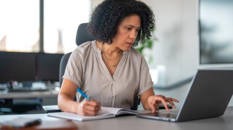 Une femme d'origine hispanique travaille sur son ordinateur portable dans son bureau