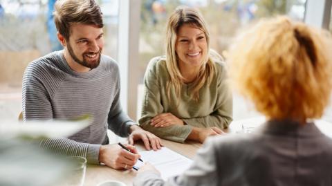 Un couple souriant valide les conditions d'un accord avec sa conseillère bancaire lors d'un rendez-vous