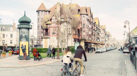 Un jeune couple arpente l'une des artères principales de Deauville à vélo