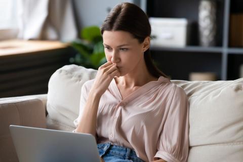 jeune femme assise sur son canapé se renseigne sur la possibilité de faire plusieurs offres d'achat sur un même bien 