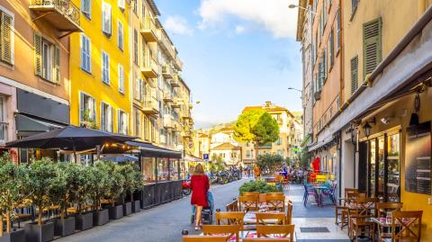 Une femme avec une poussette se promène dans une rue du Vieux Nice