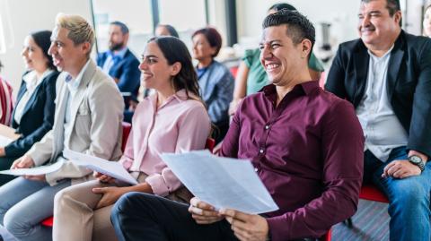 Un groupe de personnes assises côte à côte, tenant la convocation dans les mains, participe à une réunion de copropriété