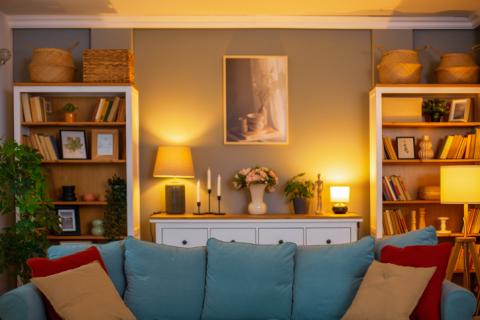 Petit salon cosy éclairé, avec un canapé bleu et des coussins rouges. 