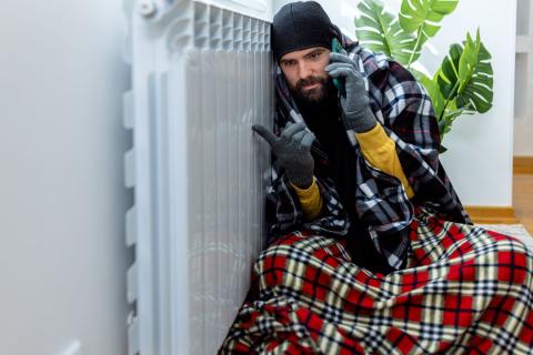 homme-emmitouflé-dans-ses-couvertures-appelle-pour faire dépanner son radiateur