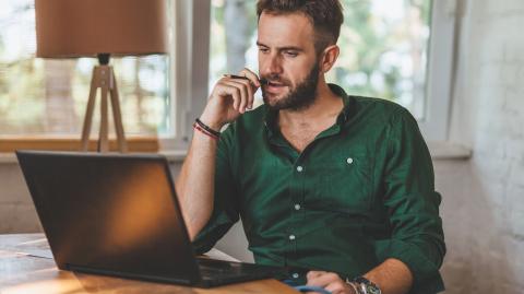Un homme effectue des démarches administratives sur son pc portable, dans son salon
