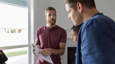Un professionnel montre à un jeune couple des informations importantes mentionnées sur un document 