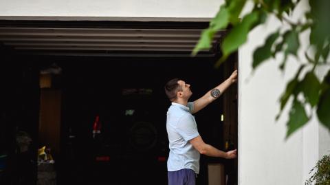 Un homme se tient à l'entrée de son garage, avec la porte ouverte sur l'intérieur
