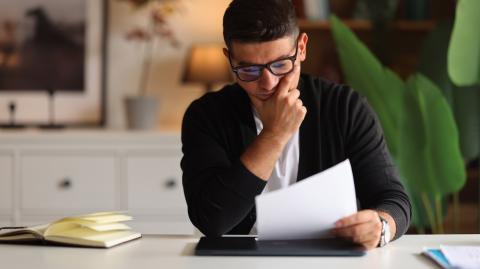 Un homme assis à un bureau découvre le contenu d'un courrier