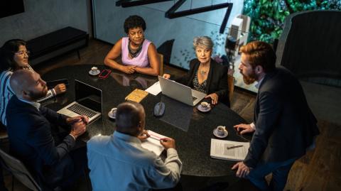 Des personnes échangent autour d'une table lors d'une assemblée générale de copropriété
