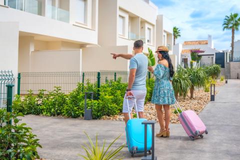 Un homme et une femme avec leurs valises colorées montrent leur lieu de vacances. 