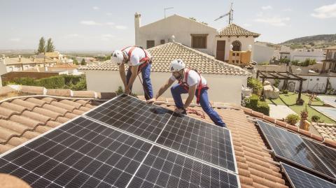 Deux ouvriers du bâtiment installent des panneaux solaires sur le toit d'une maison