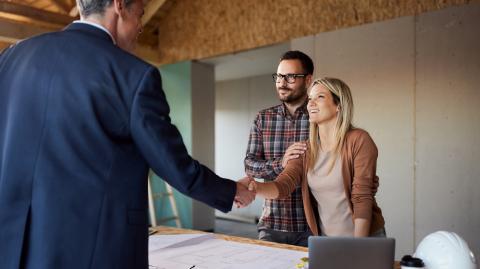 Un couple convient d'un accord avec un professionnel de la construction en lui serrant la main dans leur maison
