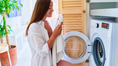 Une femme sort du linge propre de son lave-linge
