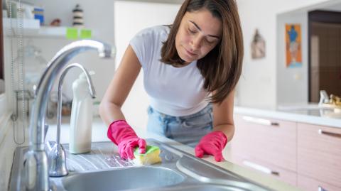 Une femme nettoie son évier en inox avec soin à l'aide d'une éponge