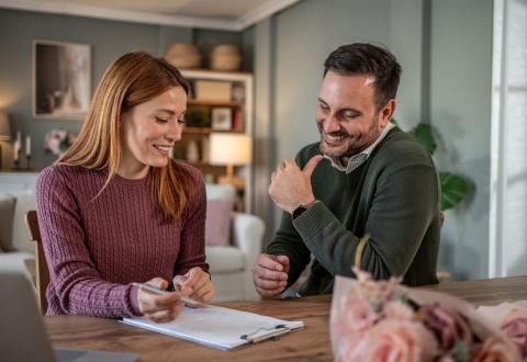 Couple d'acquéreurs signant l'acte de vente d'un bien immobilier.
