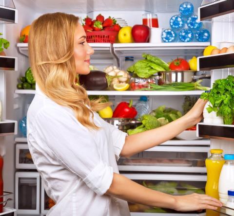 Une femme organisant l'intérieur de son réfrigérateur