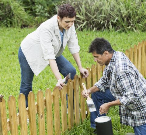 Un homme et une femme installent une petite clôture en bois commune en limite de leur terrain