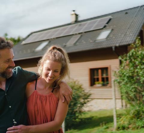 Un couple enlacé se tient devant sa maison bioclimatique
