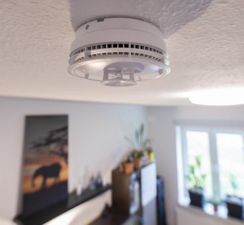 Un détecteur de fumée est fixé au plafond dans une pièce de vie