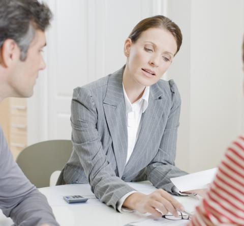 Une femme donne des explications à un couple de clients sur des documents au format papier