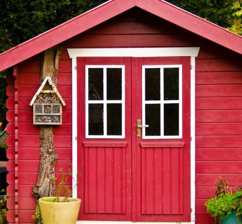 Petite maisonnette en bois rouge servant d'abri de jardin, en limite de propriété