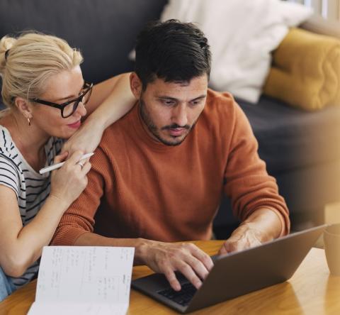 Un couple effectue des recherches sur un ordinateur portable, dans son salon
