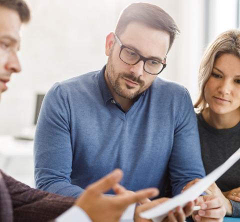 Un couple étudie des documents avec son banquier lors d'un rendez-vous
