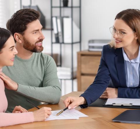 Un jeune couple consulte les documents remis par son notaire au cours d'un rendez-vous pour la signature d'un acte de vente