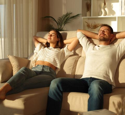 Jeune couple profite du soleil à l'aise dans le canapé du salon