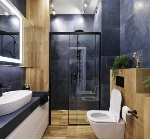 Belle salle de bain en carrelage bleu et meubles en bois. 