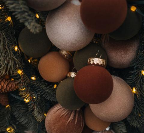 Boules de Noël allant du brun au safran accrochées sur un sapin