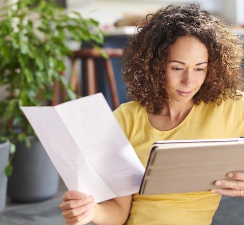 Une femme aux cheveux bouclés consulte ses comptes sur une tablette