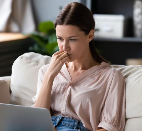 jeune femme assise sur son canapé se renseigne sur la possibilité de faire plusieurs offres d'achat sur un même bien 