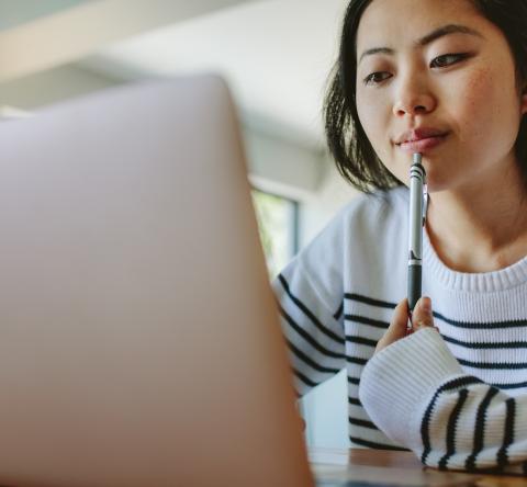 Une jeune femme d'origine asiatique fait des recherches sur son ordinateur
