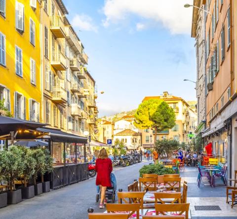 Une femme avec une poussette se promène dans une rue du Vieux Nice