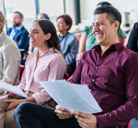 Un groupe de personnes assises côte à côte, tenant la convocation dans les mains, participe à une réunion de copropriété