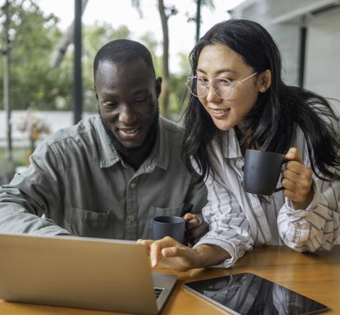 Un jeune couple complète un questionnaire en ligne sur un pc portable dans son salon