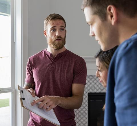 Un professionnel montre à un jeune couple des informations importantes mentionnées sur un document 