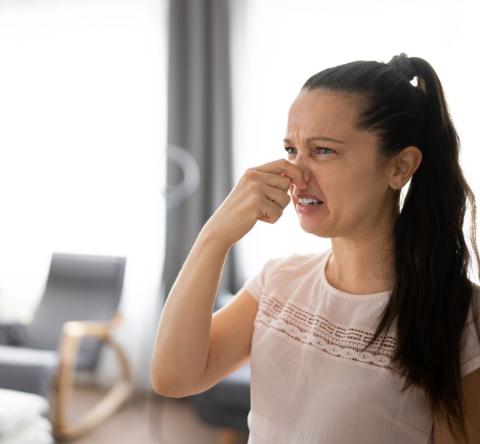 Femme grimaçant à cause d'une odeur d'égout dans sa maison