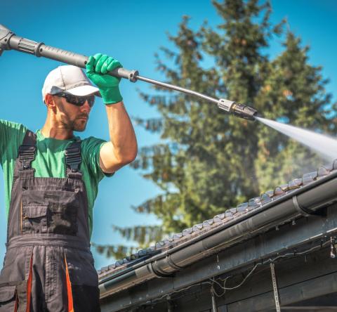 Homme nettoie la toiture sans monter sur le toit