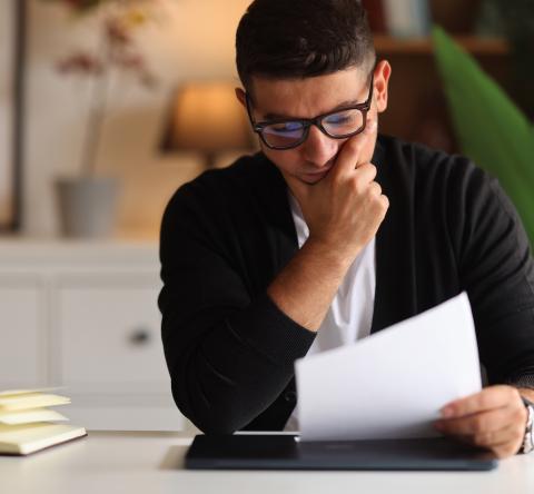 Un homme assis à un bureau découvre le contenu d'un courrier
