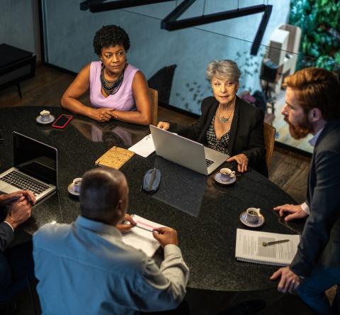 Des personnes échangent autour d'une table lors d'une assemblée générale de copropriété