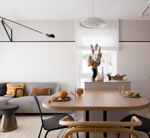 Joli salon avec canapé d'angle gris et table en bois au premier plan. 